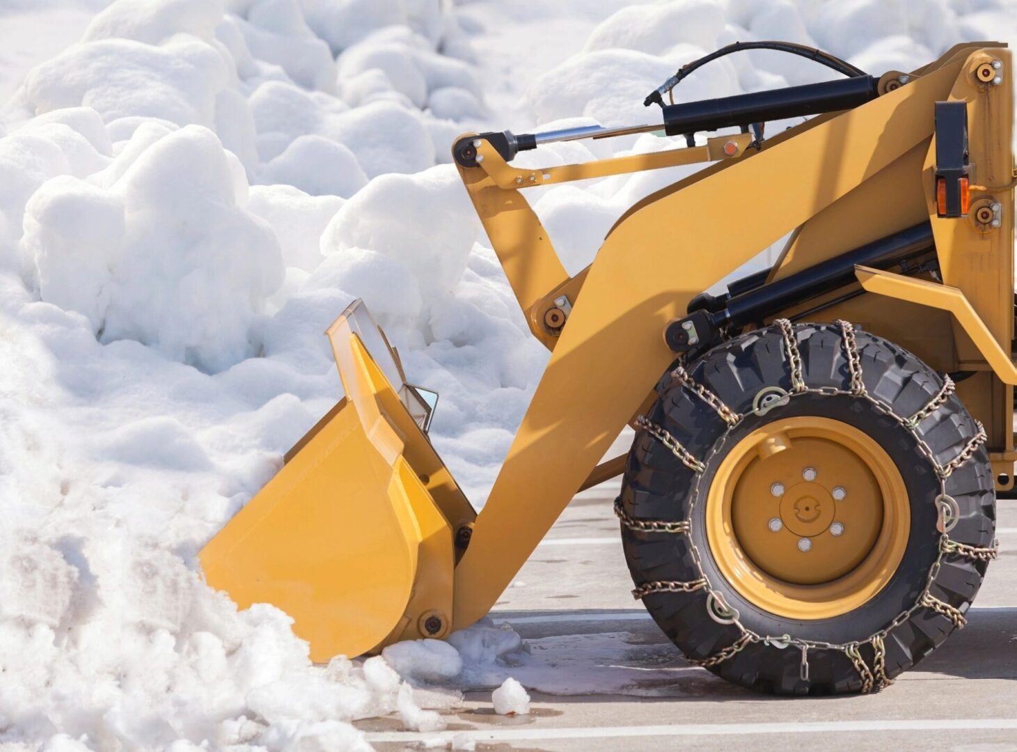 A yellow wheel loader is parked in the snow.